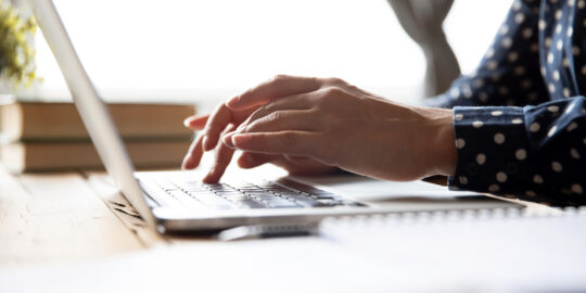 Female SAP Program Manager hands typing on a laptop